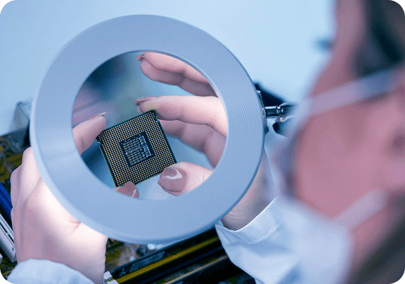 Engineer examining microchip through magnifying glass